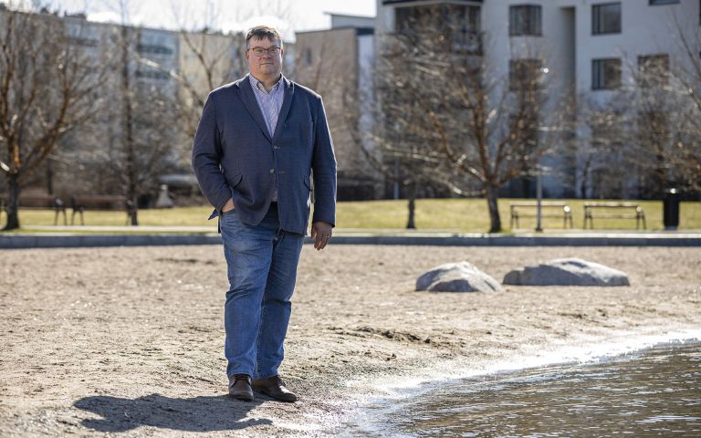 SansOx Oy:n toimi­tus­johtaja Mikael Seppälä seisomassa Vesijärven rannalla keväisessä maisemassa.