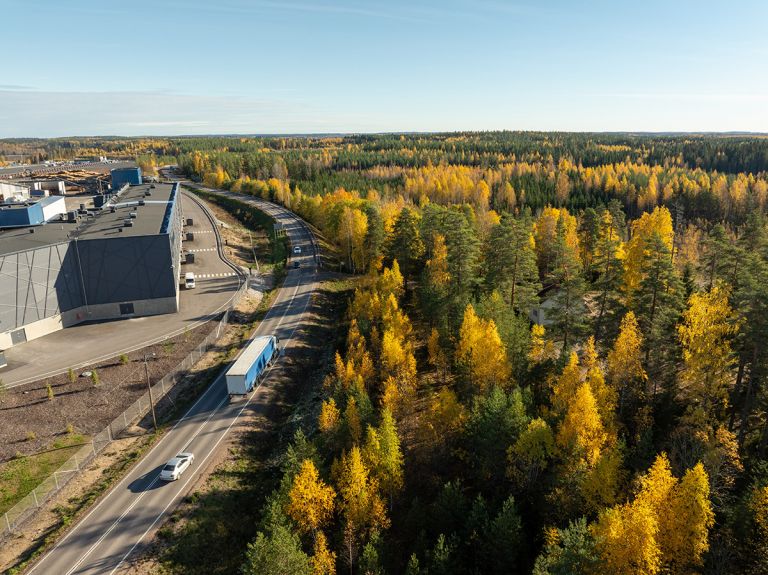 An industrial building next to a highway, with a truck on the road.