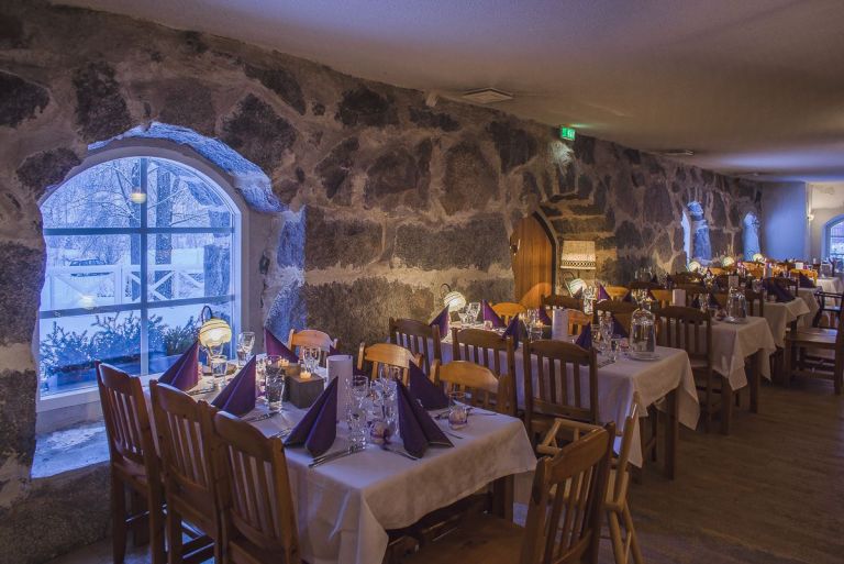 Pyhäniemen kartanonen keltainen päärakennus, etualalla vihreä nurmi ja puiston puita.