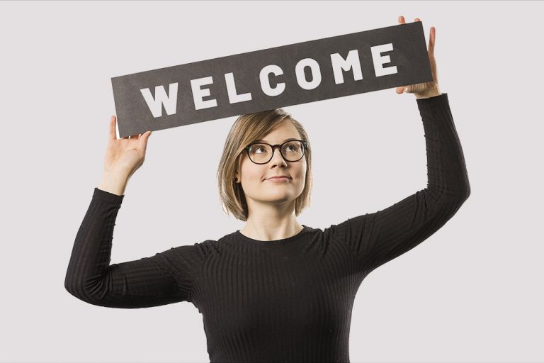 A woman holding a welcome sign.