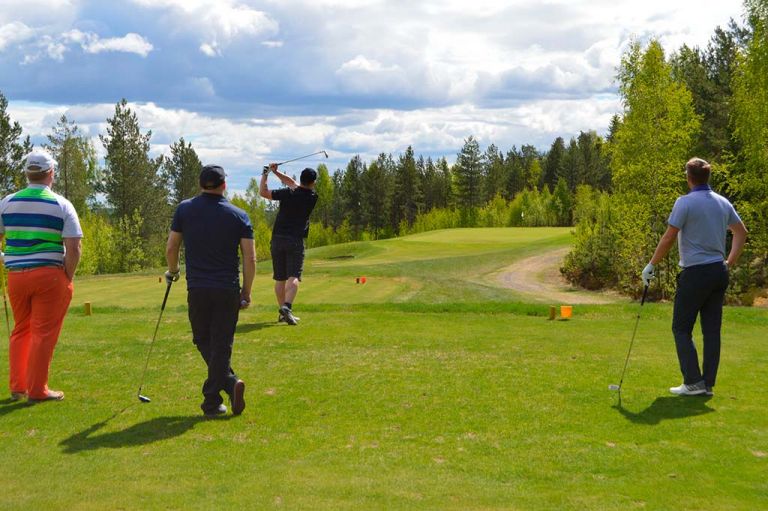 Kuva: VisitLahti.fi Aurinkoisen golfkentällä neljä miespelaajaa.